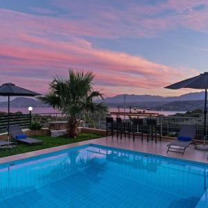 a swimming pool with a view of the ocean at sunset at Villa Roula 3BR Seaview Villa in Chania in Stérnai