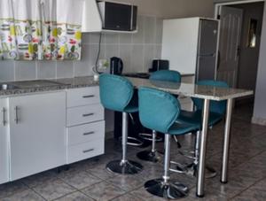 a kitchen with four blue chairs and a counter at Seaview Unit 3 in Port Shepstone