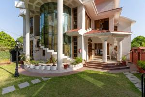 a large white house with plants in a yard at PleasantVille by VEO - Part of StayVista in Nāhan
