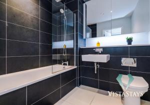 ein Badezimmer mit einem Waschbecken, einer Badewanne und einem WC in der Unterkunft Modern 2 Bed Apartment with Pool Table by Vista Stays Short Lets Manchester in Manchester