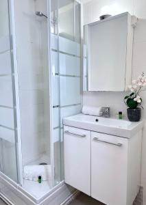 ein weißes Bad mit einer Dusche und einem Waschbecken in der Unterkunft 1601 - Charming studio in Paris Olympic Games 2024 in Paris