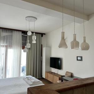 a bedroom with a bed and a tv and pendant lights at Apartments Lungo Mare in Sveti Stefan