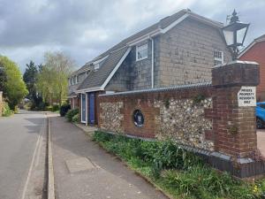 a brick house with a sign on it next to a street at Arundel Central Apartment with parking in Arundel