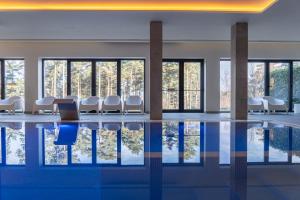 a room with a pool with chairs and windows at Pena Park Hotel in Ribeira de Pena