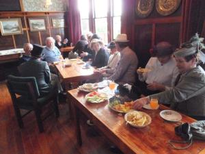 Eine Gruppe von Menschen, die an einem Tisch sitzen und Essen essen. in der Unterkunft Federation House in Oamaru