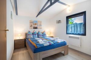 a bedroom with a bed with blue sheets and a window at Bungalow Netzboden, Bgl 28 in Dranske