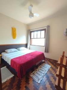 een slaapkamer met een groot bed en een rode deken bij Recanto Jacarandá in Ouro Fino