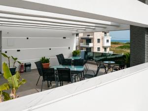 d'une terrasse avec des tables et des chaises sur un balcon. dans l'établissement Grand Wave Luxury Suites, à Flogita