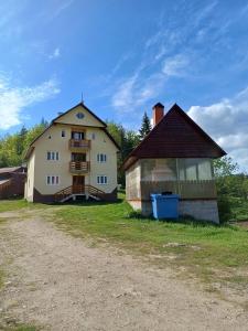 una gran casa blanca y un granero en un campo en Pensiunea Poarta Lui Ionele, en Gârda de Sus