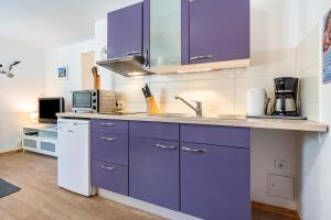 una cocina con armarios morados y fregadero en Bungalow 'zur Möwe' - Bgl 22, en Dranske 13 fotos más