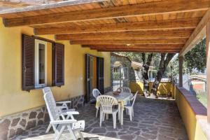 a patio with a table and chairs under a wooden pergola at Casa Ilva - Colle Paradiso Experience in Capoliveri +1 photo
