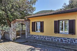 a yellow house with a gate and windows at Casa Ilva - Colle Paradiso Experience in Capoliveri