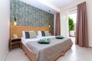 una camera da letto con un grande letto con due cuscini sopra di Emerald Hotel a Mália