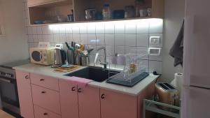 een roze keuken met een wastafel en een magnetron bij Gil's Home of Joy & Serenity in Haifa