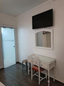 een kamer met een bureau en een tv aan de muur bij Hostel Boutique Marisol in Monte Gordo