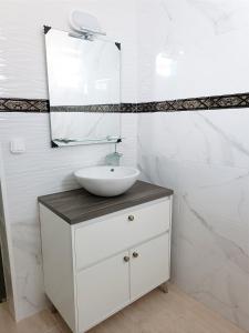een witte badkamer met een wastafel en een spiegel bij Hostel Boutique Marisol in Monte Gordo