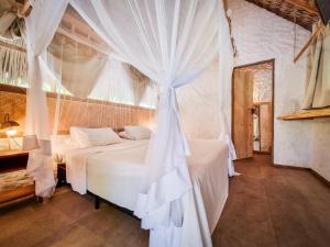 een slaapkamer met een bed met een klamboe bij Vila do Junco in Santo Amaro