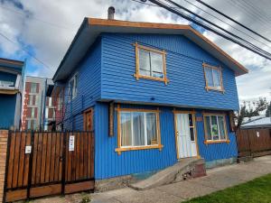 a blue house with a fence in front of it at Fungi Hostal in Coihaique