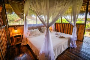 ein Schlafzimmer mit einem weißen Bett mit Baldachin in der Unterkunft Vila do Junco in Santo Amaro