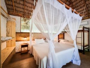 a bedroom with a bed with white mosquito netting at Vila do Junco in Santo Amaro