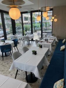 een restaurant met witte tafels, stoelen en ramen bij Hotel Atlanta Knokke in Knokke-Heist