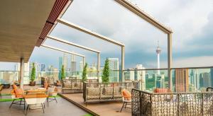 uma varanda com cadeiras e mesas e vista para a cidade em Hilton Garden Inn Kuala Lumpur - South em Kuala Lumpur
