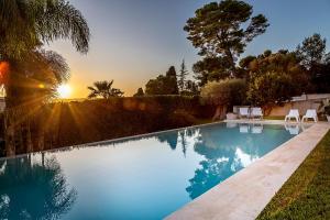 a swimming pool with two chairs and the sunset at Attalàya, oasi di relax con piscina vicino Noto in Noto