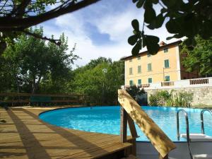 uma piscina com um deque de madeira e um edifício em Lovely holiday home in Montefiridolfi with hill view em Montefiridolfi