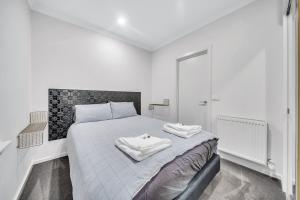 ein weißes Schlafzimmer mit einem Bett mit zwei Handtüchern darauf in der Unterkunft Grosvenor 3121 Richmond in Melbourne