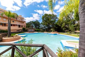 a swimming pool in a resort with a wooden fence at ALTAVISTA ISLANTILLA GOLF by MSHOLIDAYS in Islantilla
