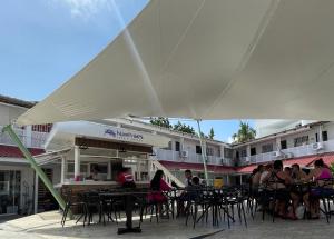 um grupo de pessoas sentadas em mesas sob um guarda-chuva branco em Island Vibes em San Andrés