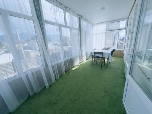 Cette chambre avec fenêtres comprend une table et des chaises. dans l'établissement Guest house B&B, à Kochkorka