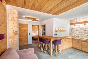 a kitchen with a wooden table and purple chairs at Tana del picchio Rosso in Falcade