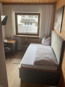 Łóżko w małym pokoju z oknem w obiekcie Landgasthof Dorfstadl w mieście Kössen