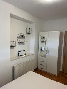 een slaapkamer met een witte kast en een klok aan de muur bij Apartments Ploka in Trogir
