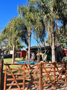 una valla de madera frente a una casa con palmeras en La casa del Rio en Sauce Viejo - Santa Fe- en Sauce Viejo