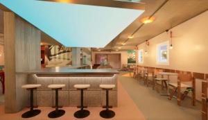 una cafetería con un bar con taburetes y mesas en Greet Hotel Nice Aéroport Promenade des Anglais en Niza