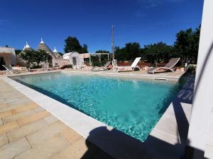 einen Pool mit blauem Wasser und Liegestühlen in der Unterkunft Trullo del Sol in Ceglie Messapica