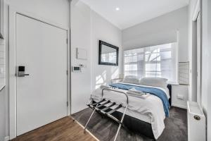 Habitación blanca con cama y espejo en Grosvenor 3121 Richmond en Melbourne