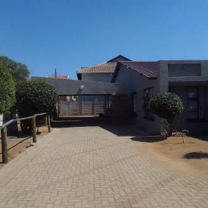 a house with a brick driveway in front of a building at The Best Moments guesthouse in Rustenburg