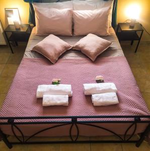ein Bett mit drei Handtüchern und Kissen darauf in der Unterkunft Olyna’s Apartment N.S Preveza in Néa Sampsoús