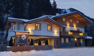una casa nella neve con le luci accese di Alpen Appartements Viehhofen a Viehhofen
