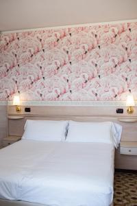 a bed with a wall covered in pink roses at Hotel Flamingo in Gatteo a Mare