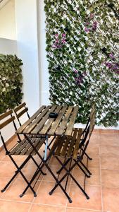 um banco e duas cadeiras em frente a uma parede com flores em Salty Home’s em Peniche