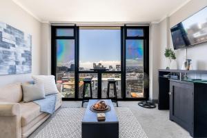 a living room with a couch and a large window at Four Seasons City Apartment ParkingPool Gym in Cape Town