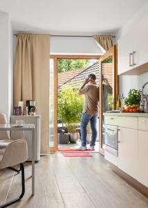 ハーゼリュンネにあるSuiten - Appartement by Studio Livingのキッチンに立ってドアの外を眺めている男性