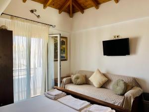 a living room with a couch and a tv at Avra Studios in Elafonisos