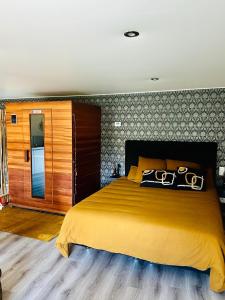 L'Entre 2 - Suite de charme avec sauna et baignoire balnéo في Amay: غرفة نوم بسرير اصفر كبير في الغرفة