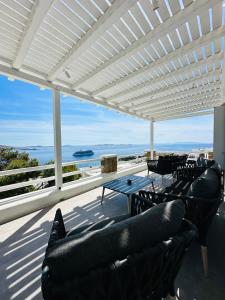 un patio con sofás y mesas y vistas al océano en Seaview & Jacuzzi summer residence en Mykonos