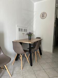 une table à manger avec des chaises et une horloge murale dans l'établissement Iris Apartment Nafpaktos, à Naupacte